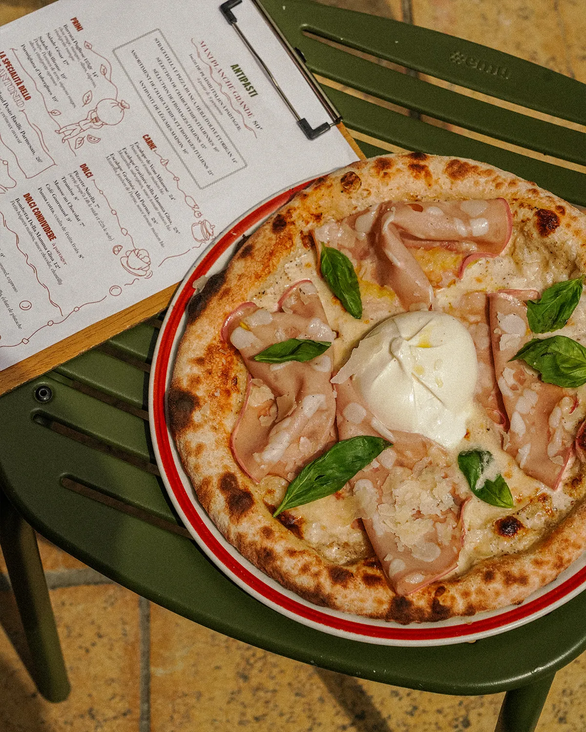 Pizza à la mortadelle, burrata et basilic, posée à côté de la carte